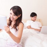 Cheerful couple using touch pad in bed