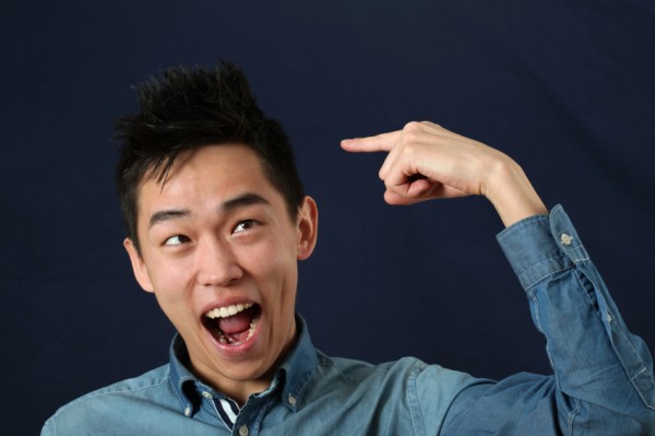 Funny young Asian man pointing the index finger at his haircut