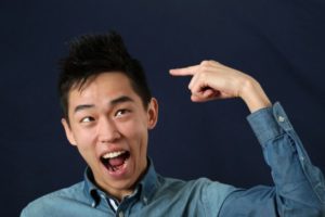 Funny young Asian man pointing the index finger at his haircut