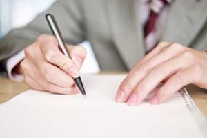 hands writing on white notebook.