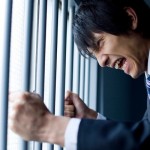 Businessman holding bars of cage and shouting