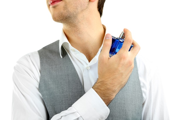 Handsome young man using perfume isolated on white