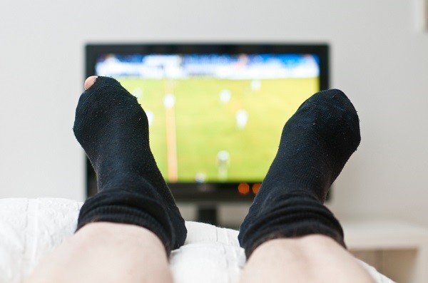 Laying in bed and watching a game on tv in dark socks with a hole