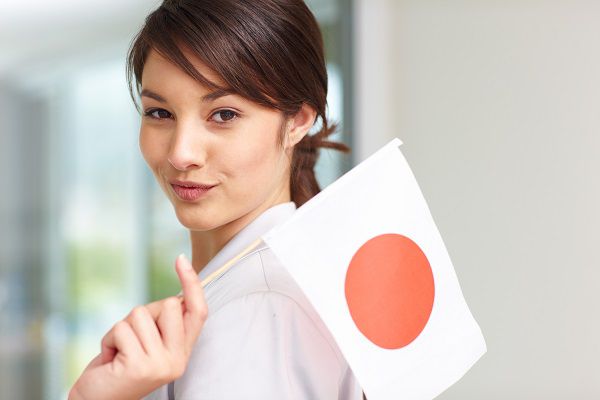Cute young woman holding Japan's flag , smiling
