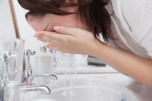 Close-up side view of woman washing face