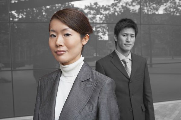 Portrait of young businesswoman with coworker outside office building