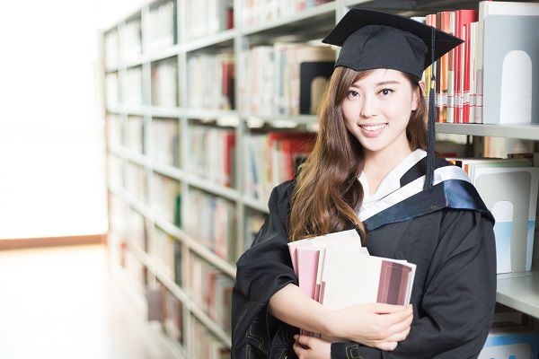 young beautiful asian girl university student with Bachelor gown in library