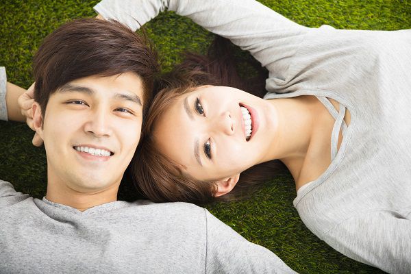 Happy Smiling Couple Relaxing on Green Grass