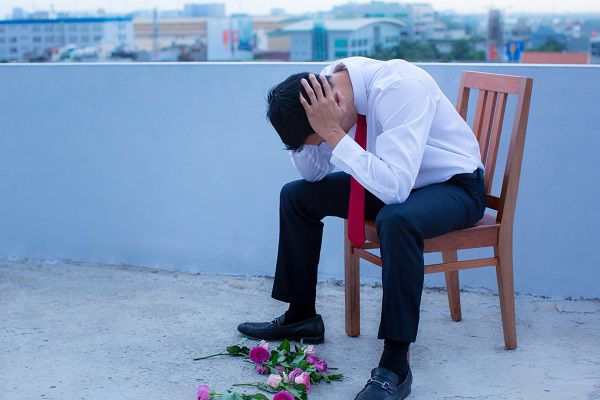 A disheartened man in a suit, broken-hearted after being rejected.