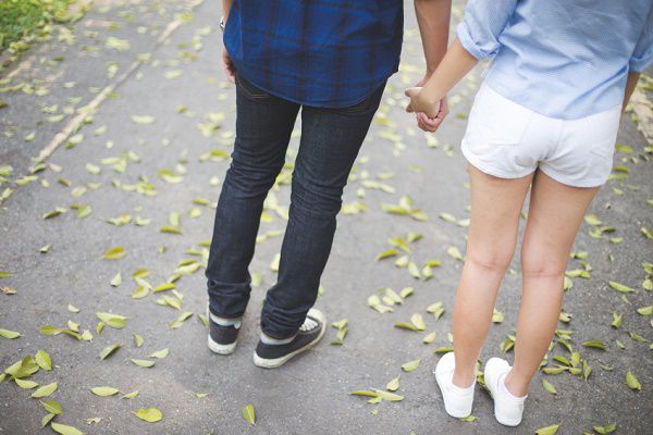 Couple hand in hand. Background of leafs on the floor.