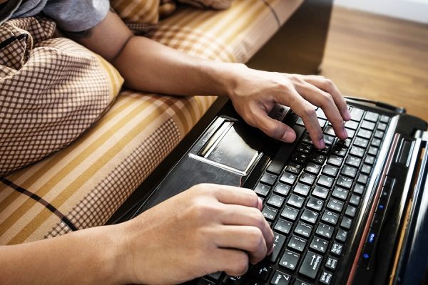 Asian guy using lap top on bed