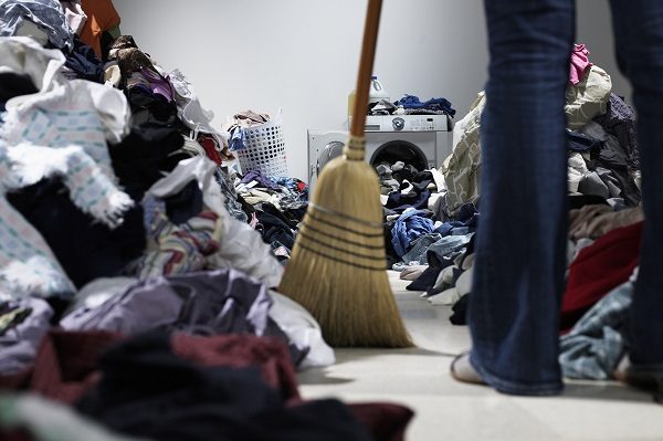 Woman sweeping pathway through piles of laundry