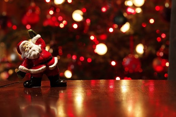 Santa figurine on table in front of Christmas tree