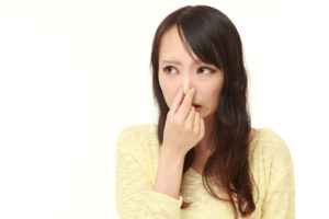 Japanese woman holding her nose because of a bad smell