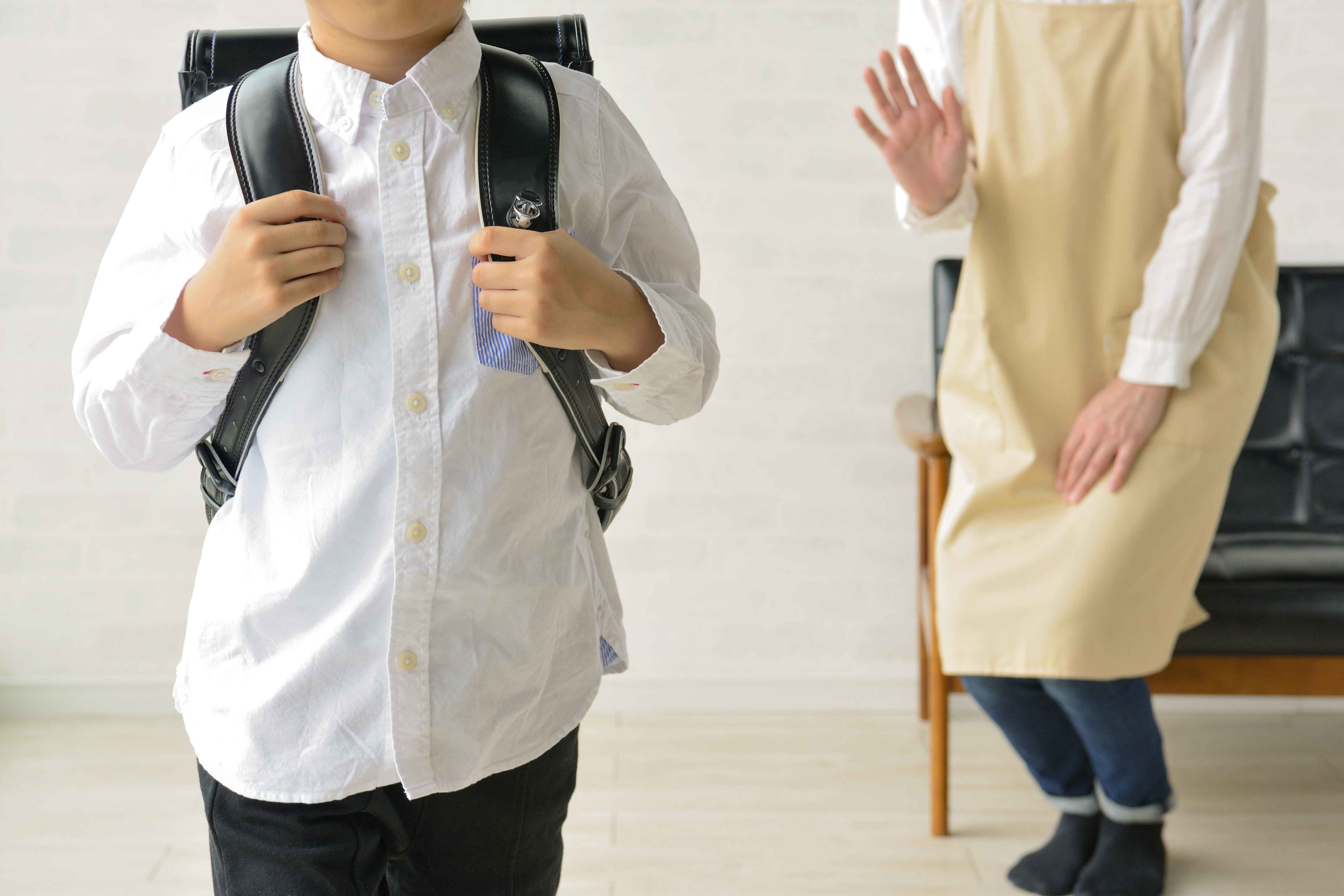 学校に行く少年と見送る母親