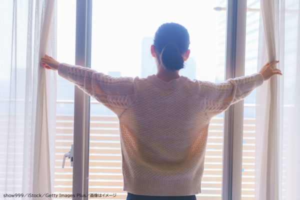 カーテンを開ける女性