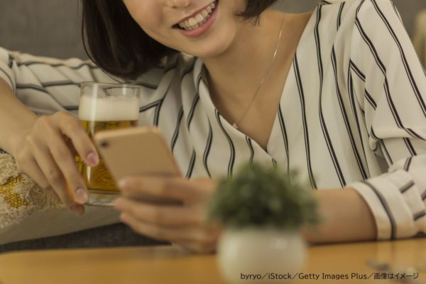 飲みながらスマホを見る女性