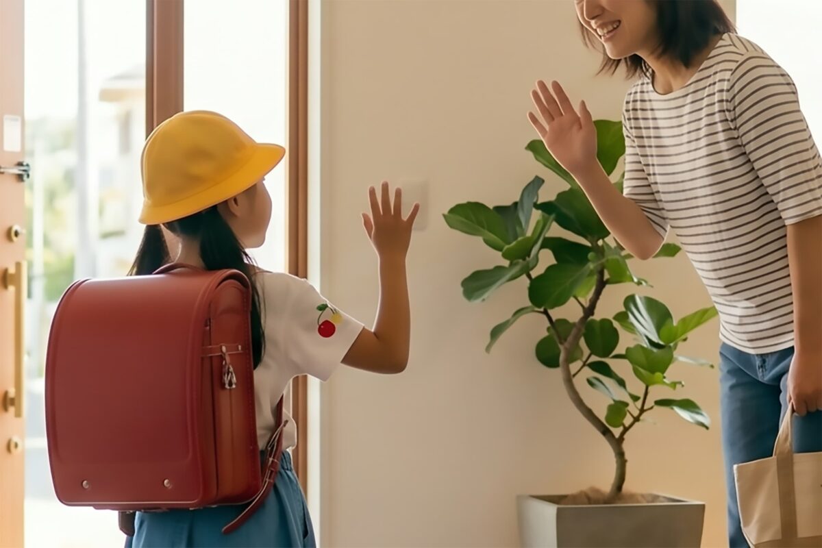 玄関で小学生の娘を送り出すイメージ